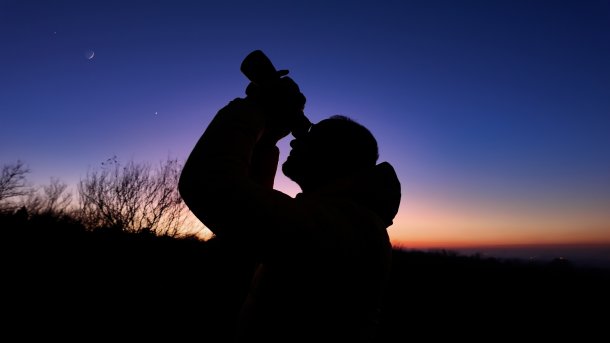 Frau mit Fernglas vor dem Nachthimmel