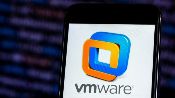 VMware-Logo auf einem Smartphone vor einem Bildschirm mit Quellcode