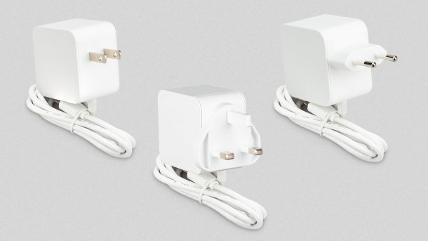 Drei Raspi-Netzteile mit unterschiedlichen Länderanschlüssen vor grauem Hintergrund