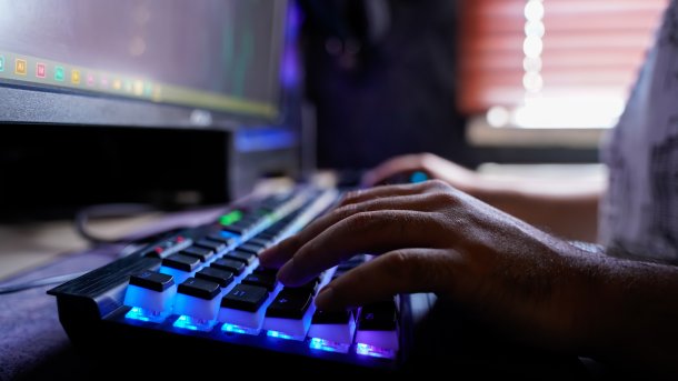 Hände auf einer beleuchteteten Tastatur