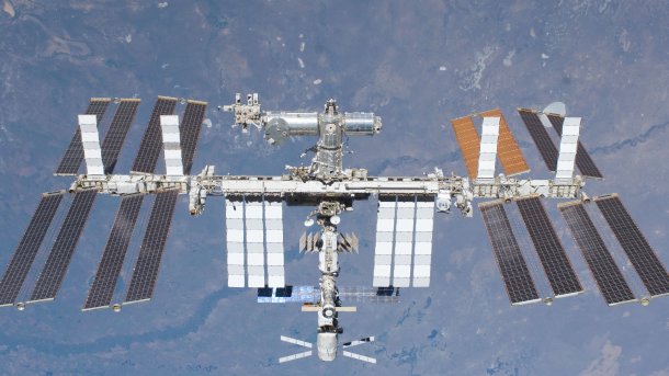 Die internationale Raumsation ISS schwebt durchs All, im Hintergrund die Erde.