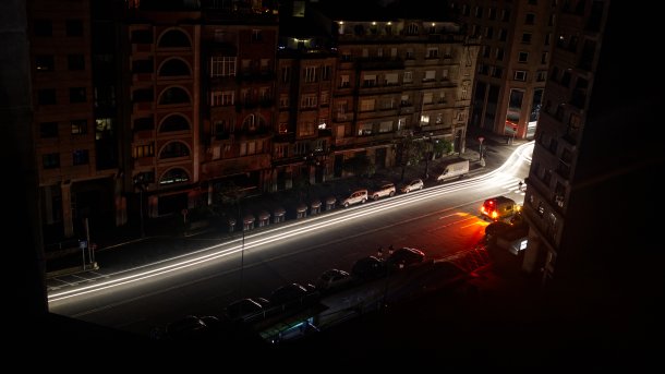 A dark city center, in the foreground the light strip of a moving car