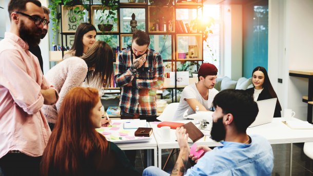 Gruppe von Menschen aus verschiedenen Ländern, die gemeinsam in einem Coworking-Space arbeiten.