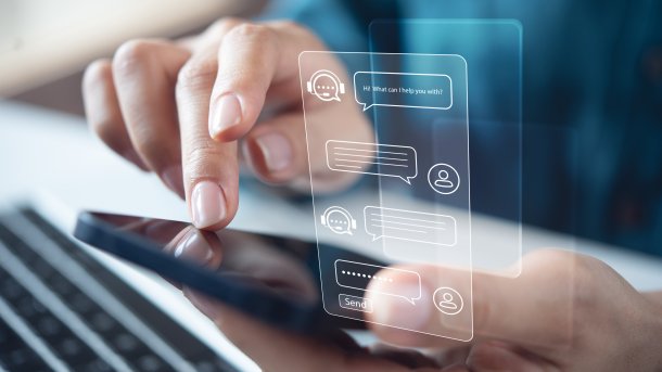 Ein Hand tippt auf einem Smartphone, darüber gelegt die Ansicht eines Chats mit einem Chatbot
