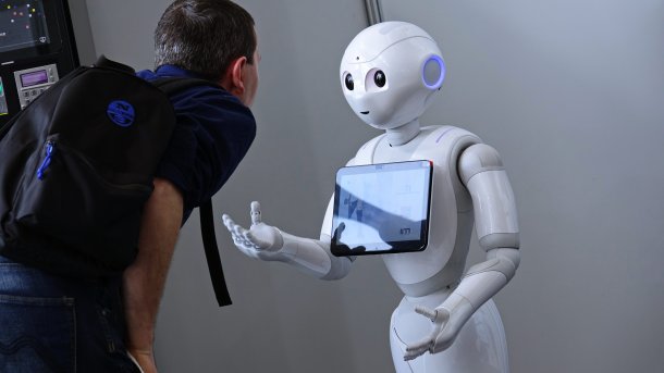 Man talks to Pepper the robot.