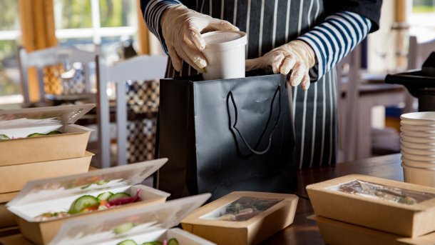 Person mit Handschuhen verpackt Salate zum ausliefern