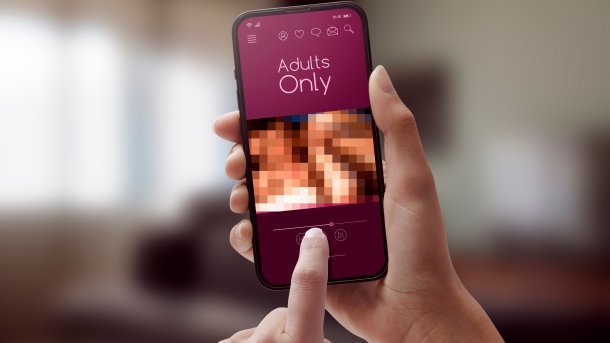 Eine junge Frau schaut ein Filmchen auf dem Smartphone.