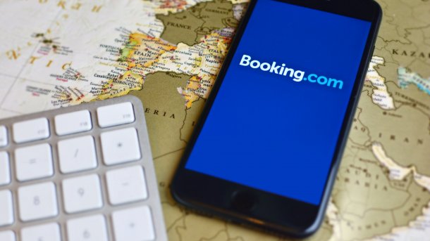 Booking.com-App auf einem Smartphone, das auf einer Weltkarte liegt.