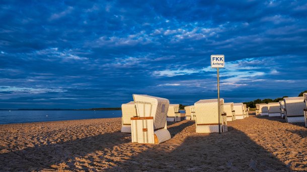 Anfang eines FKK-Strands mit Strandkörben im Hintergrund.