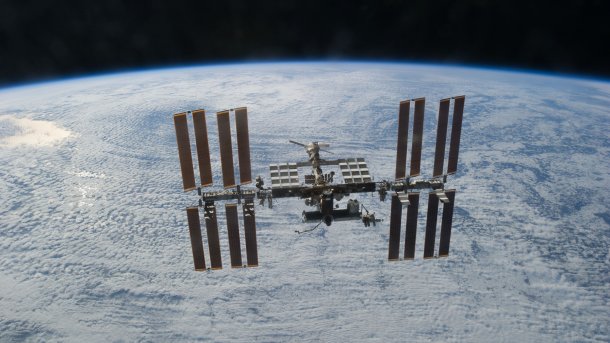 ISS schwebt über der wolkenbedeckten Erde
