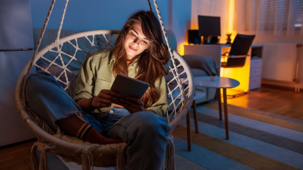 Frau sitzt in einer Art Hängematte und liest auf einem Reader