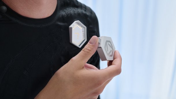 Person trägt den Exopulse Suit und hält den zugehörigen Akku in der Hand.