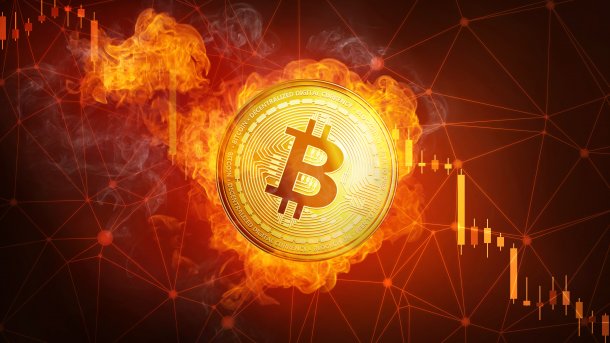 Ein brennender Bitcoin, im Hintergrund eine fallende Kurskurve