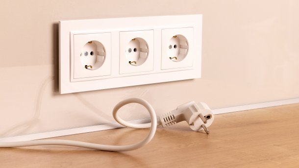 Triple socket outlet in a wall, with a power cable underneath