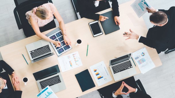 Vogelperspektive eines Konferenztisches mit mehreren Leuten