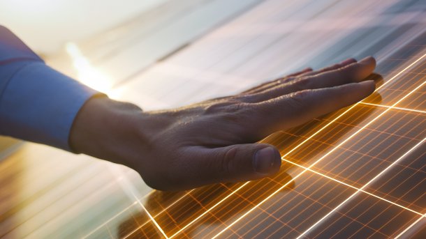 Nahaufnahme einer Hand auf einem Solarpaneel mit leuchtenden Linien