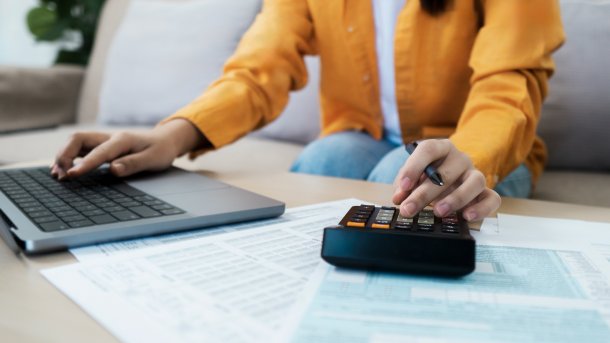 Frau tippt auf Laptop und Taschenrechner
