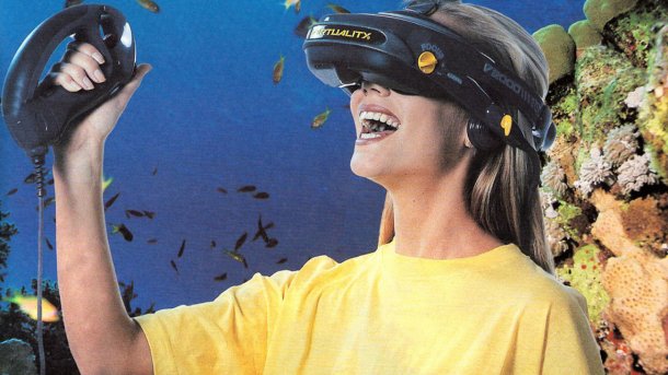A young woman wears VR goggles with a smile and holds a controller in her hand. A coral reef in the background.