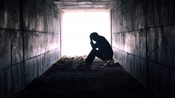 Depressed man in a tunnel with light at the end