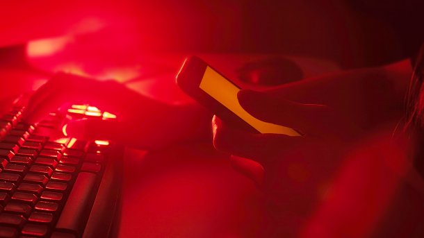 In the red light: one hand on the keyboard, the other hand on the cell phone