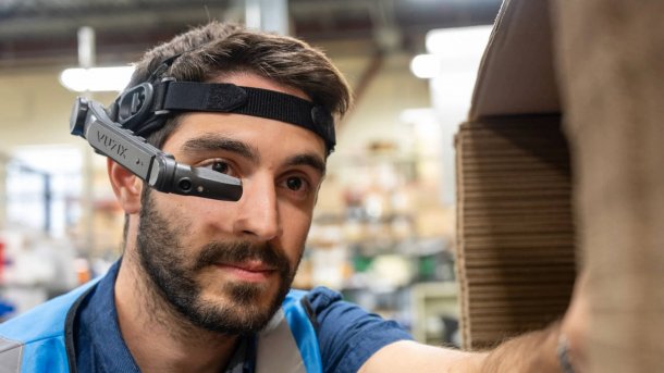 Ein Lagerarbeiter mit einem Headset, von dem ein Bügel vor sein Auge reicht. 