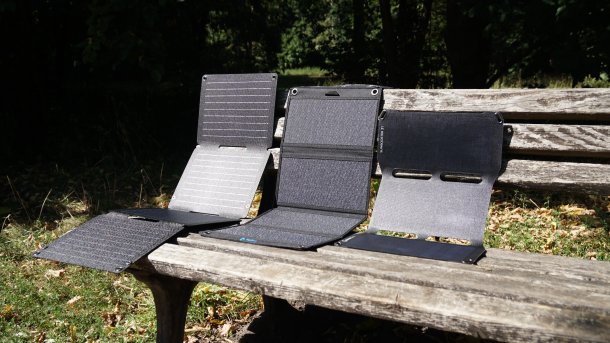 Solarladegeräte auf eine Parkbank. Wir haben drei Produkte von Anker, Bigblue und Sunnybag getestet. 