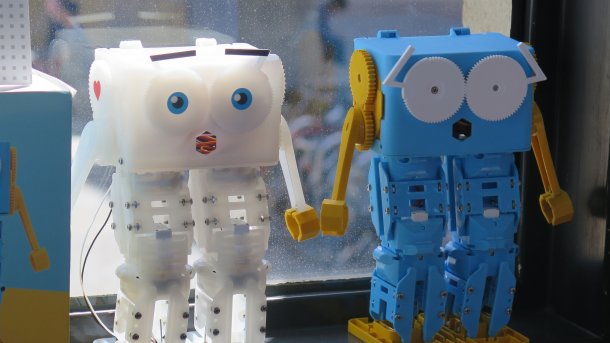 1 white and 1 light blue robot standing on a windowsill