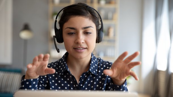 Woman with headset gestures at her laptop