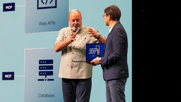 Zwei Männer auf einer Bühne präsentieren ein Notebook