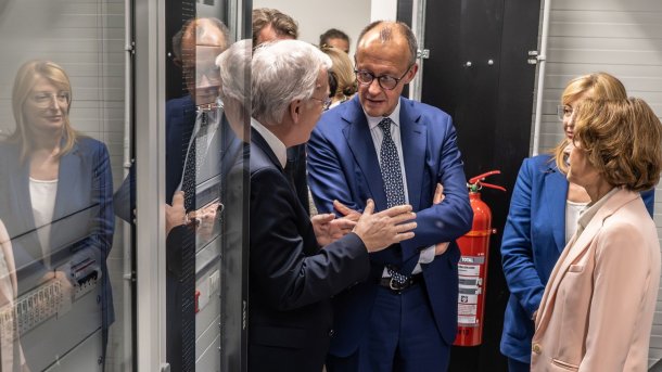 Friedrich Merz steht mit Kollegen vor einem Supercomputer-Rack