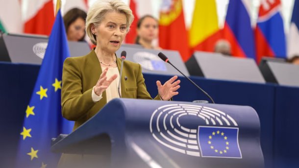 Ursula von der Leyen steht spreched an einem Rednerpult mit dem Logo des Europäischen Parlaments; im Hintergrund Flaggen verschiedener Mitgliedsstaaten.