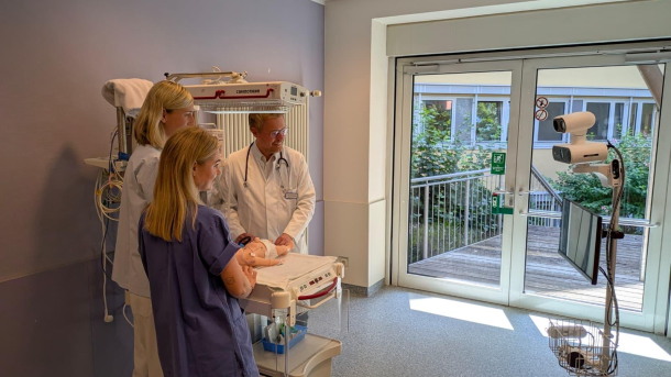 Team around Dr. Christian Bayer in a room with a simulation manikin. Next to it a telemedical device