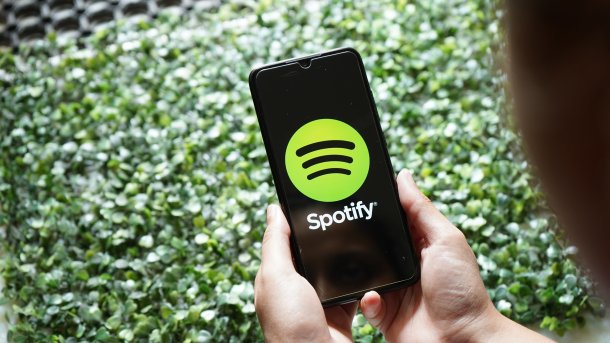 Person holds smartphone and opens Spotify app