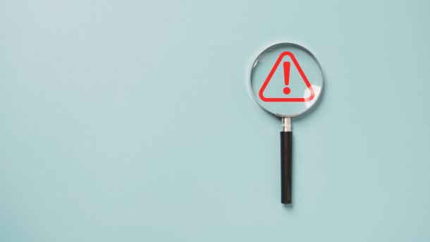 Magnifying glass with a warning triangle underneath.