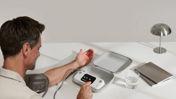 Man with electronic blood pressure monitor tapping on screen