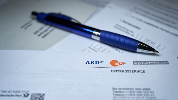 Stift liegt auf Brief, der über Rundfunkbeitrag informiert
