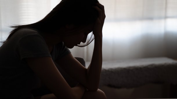 Silhouette of a woman suffering, holding her head in her hands.