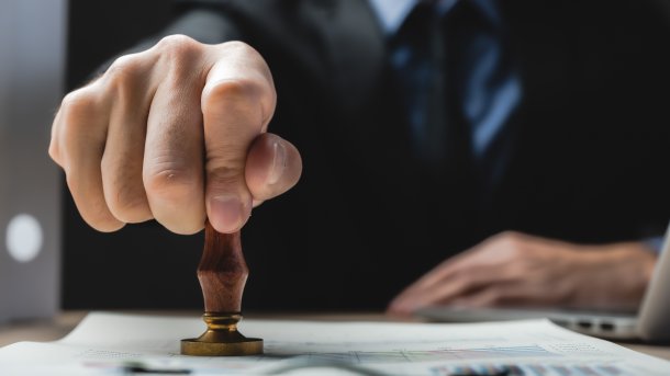 Eine Person drückt einen Stempel auf ein Dokument