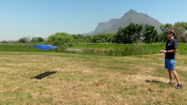 Solardrohne fliegt, reckts am Boden steht der Pilot