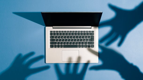 Shadows of hands reaching for a laptop