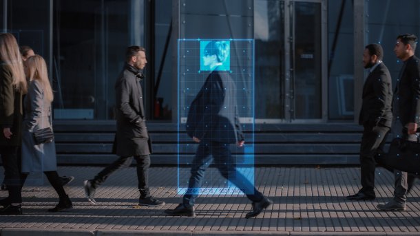 People walking on a street. Side view. One is being tracked.