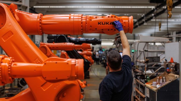Mann fasst Kuka-Roboter an
