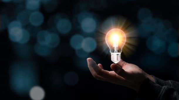 An open hand holds a glowing light bulb