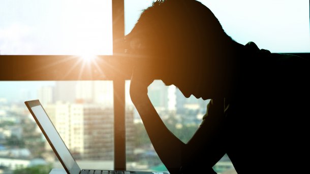 A person sits hunched over a laptop.