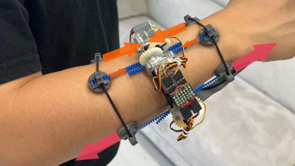 Prototyp eines mechanischen VR-Tracking-Armbands mit Zahnrädern und Sensoren auf einem Unterarm, durch Pfeile gekennzeichnete Bewegungsrichtungen.
