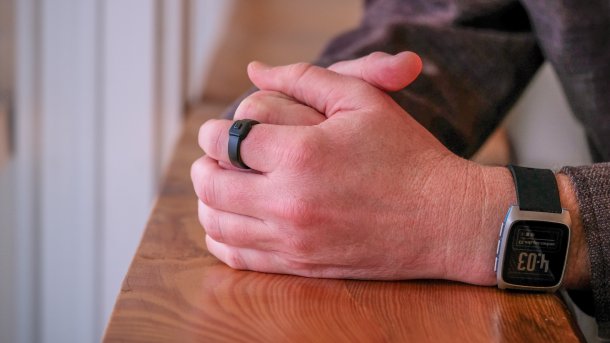 Männerhände; am Zeigefinger der linken Hand ist ein schwarzer Ring mit Druckknopf