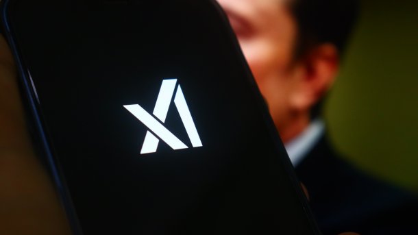 Das Logo von xAI, im Hintergrund die Silhouette von Elon Musk