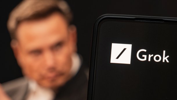 Silhouette Elon Musks hinter einem Smartphone mit dem Grok-Logo