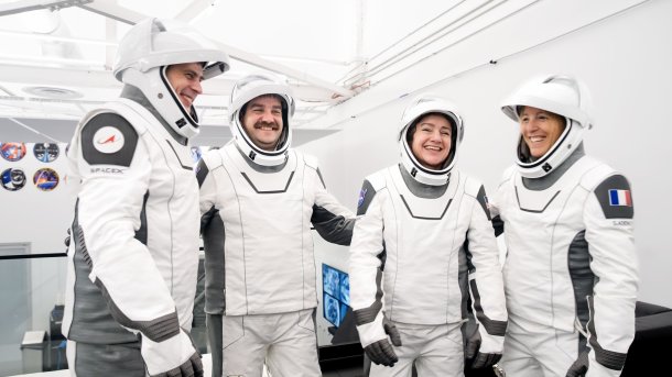Four people in white spacesuits