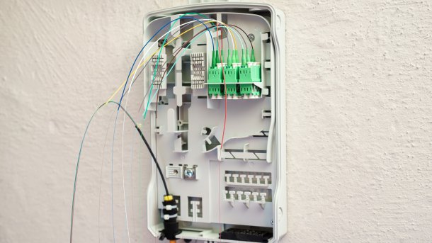 Ein geöffneter Glasfaser-Übergabepunkt im Keller eines Hauses mit sichtbarer Glasfaser-Zuleitung und den Adern für die verschiedenen Endpunkte.